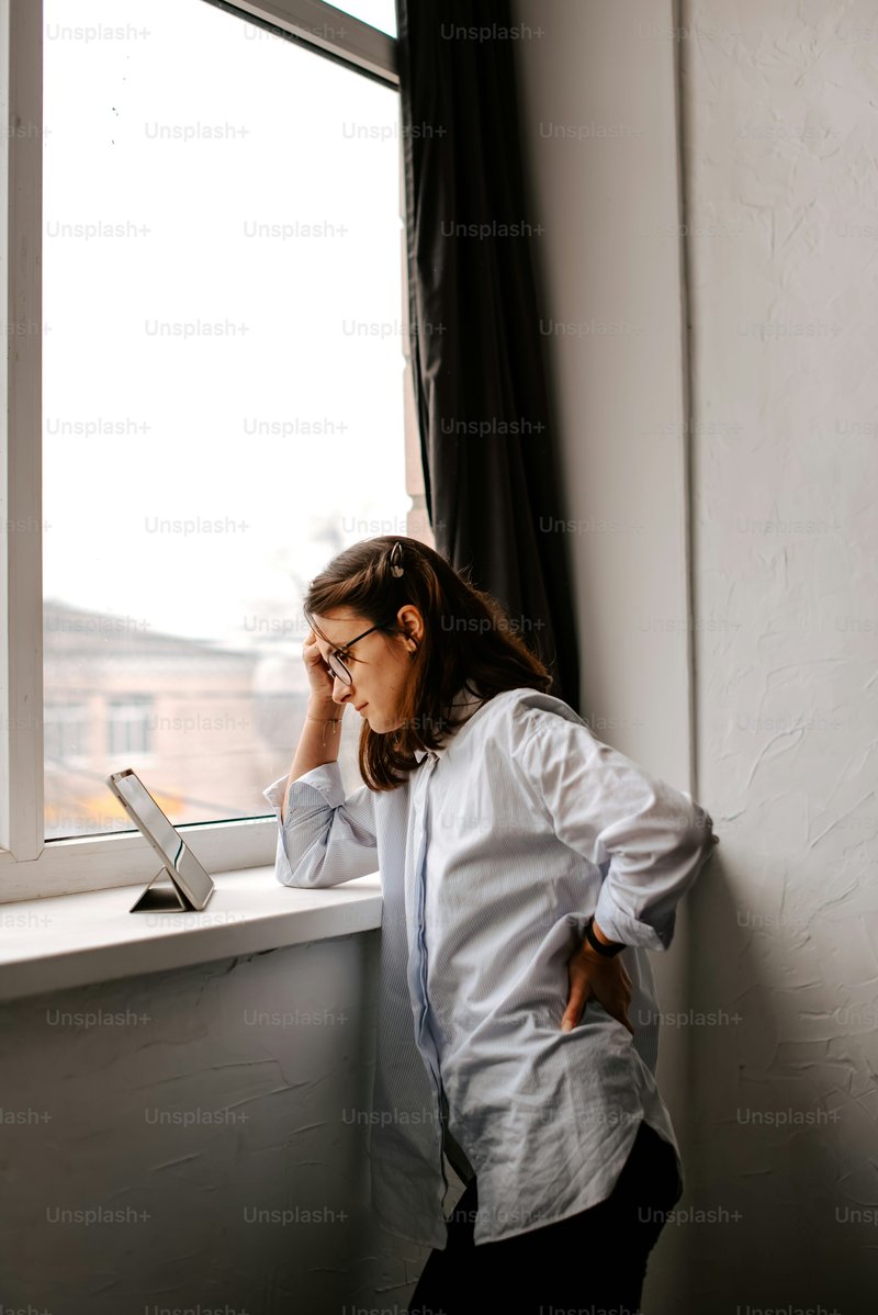 A woman leaning against a window sill while talking on a cell phone photo – Technology Image on Unsplash
