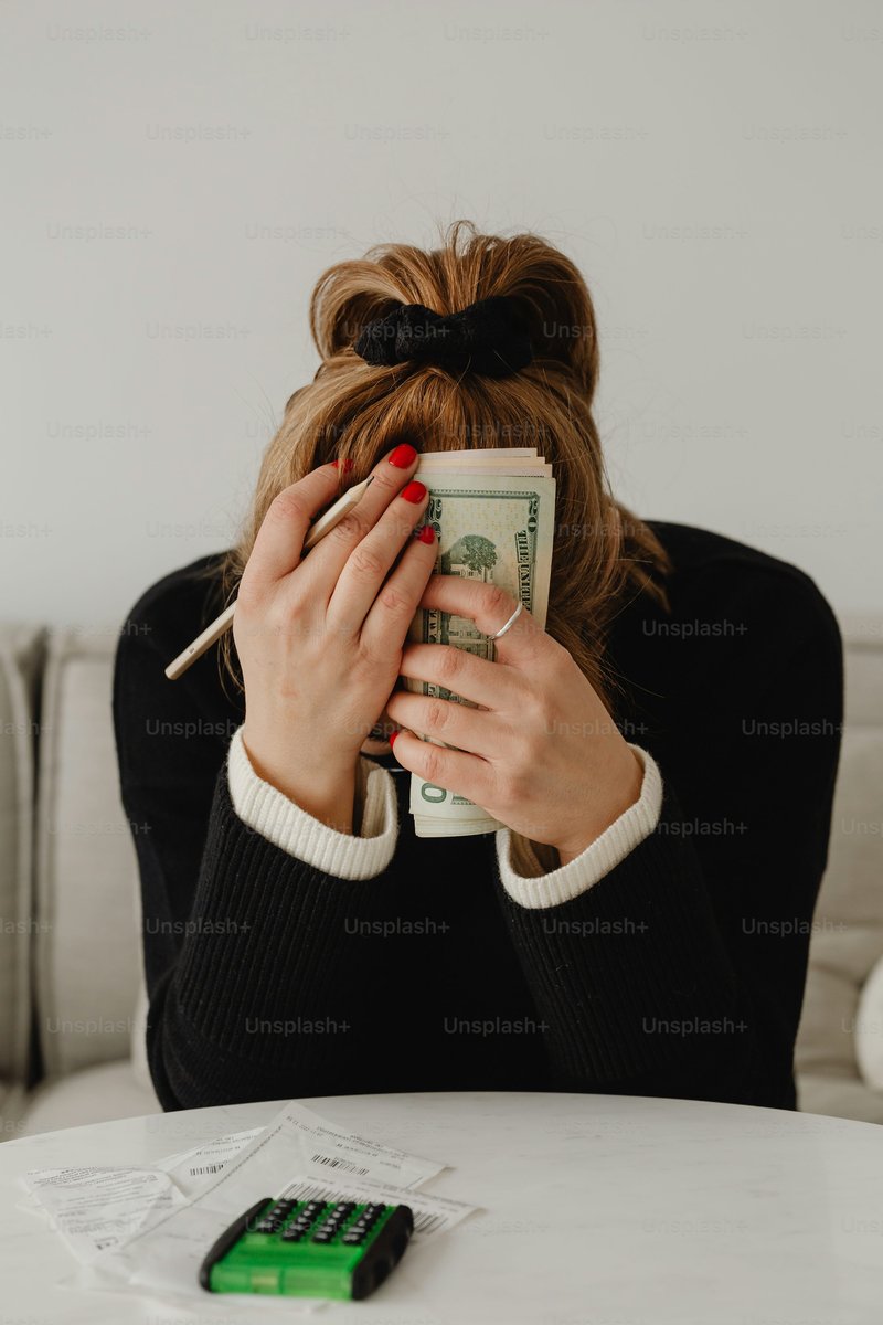 A woman sitting at a table holding a stack of money photo – Money Image on Unsplash