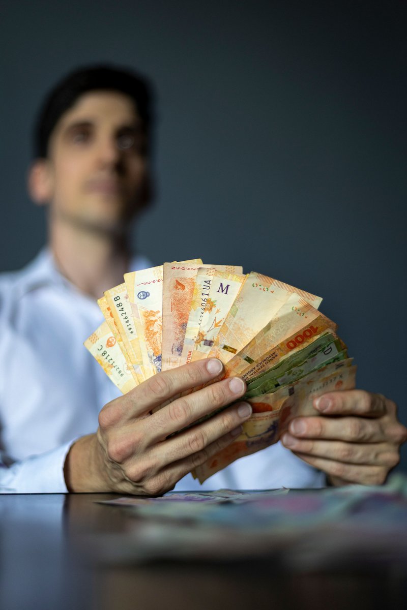 Close-up of Man Holding Argentine Peso Banknote · Free Stock Photo