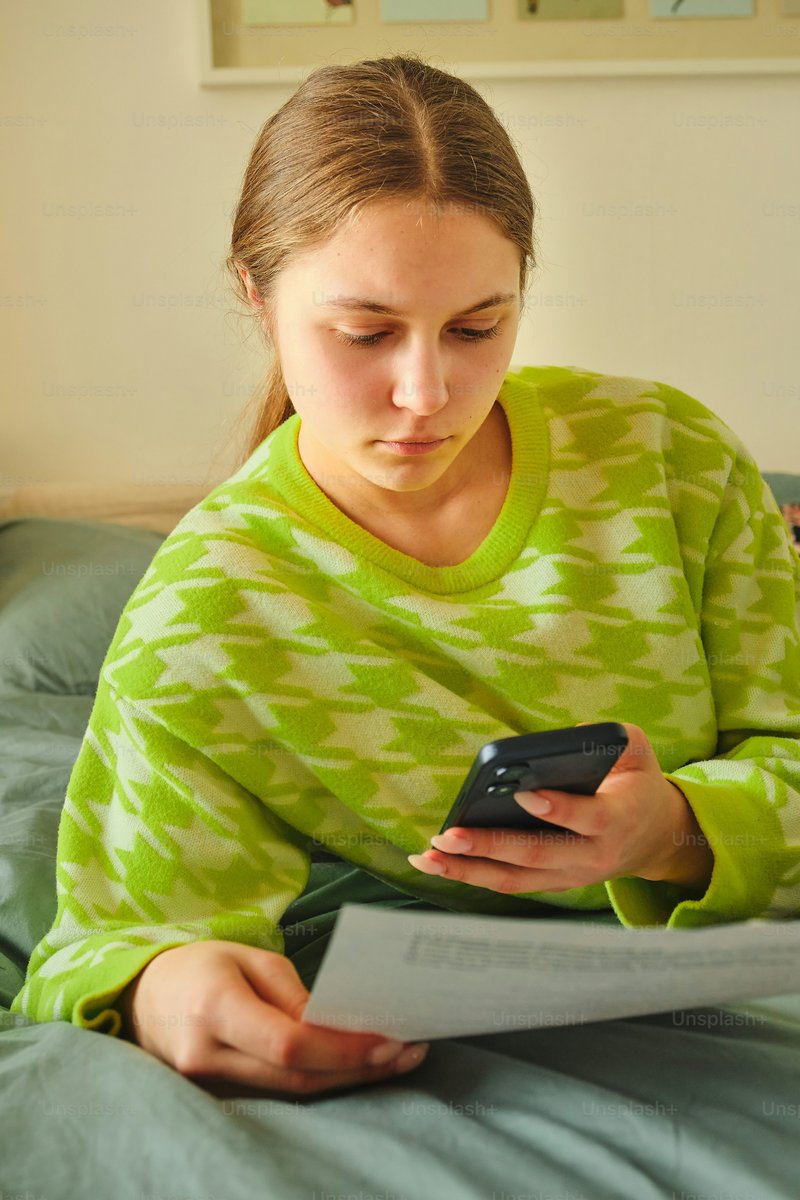 Young woman looking at phone while holding papers photo – Paper Image on Unsplash