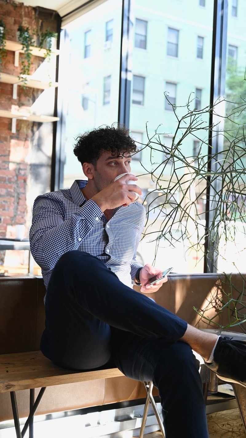 A Man Drinking Coffee while Holding a Cellphone A Man Drinking Coffee while Holding a Cellphone