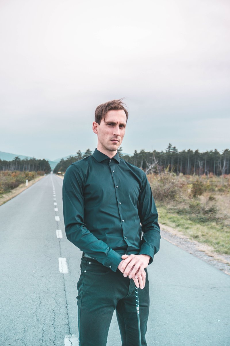 A Serious Man in Black Long Sleeves Looking at Camera while Standing on the Road · Free Stock Photo