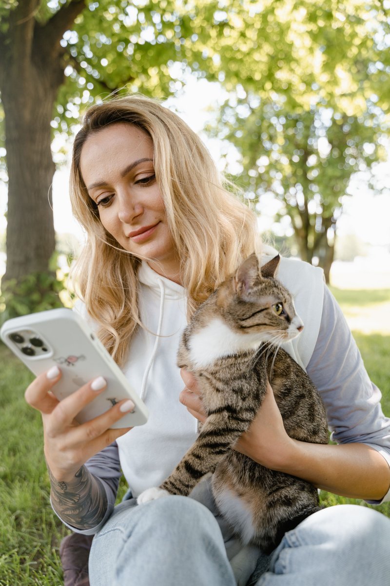 A Woman Using Her Phone while Holding Her Cat · Free Stock Photo