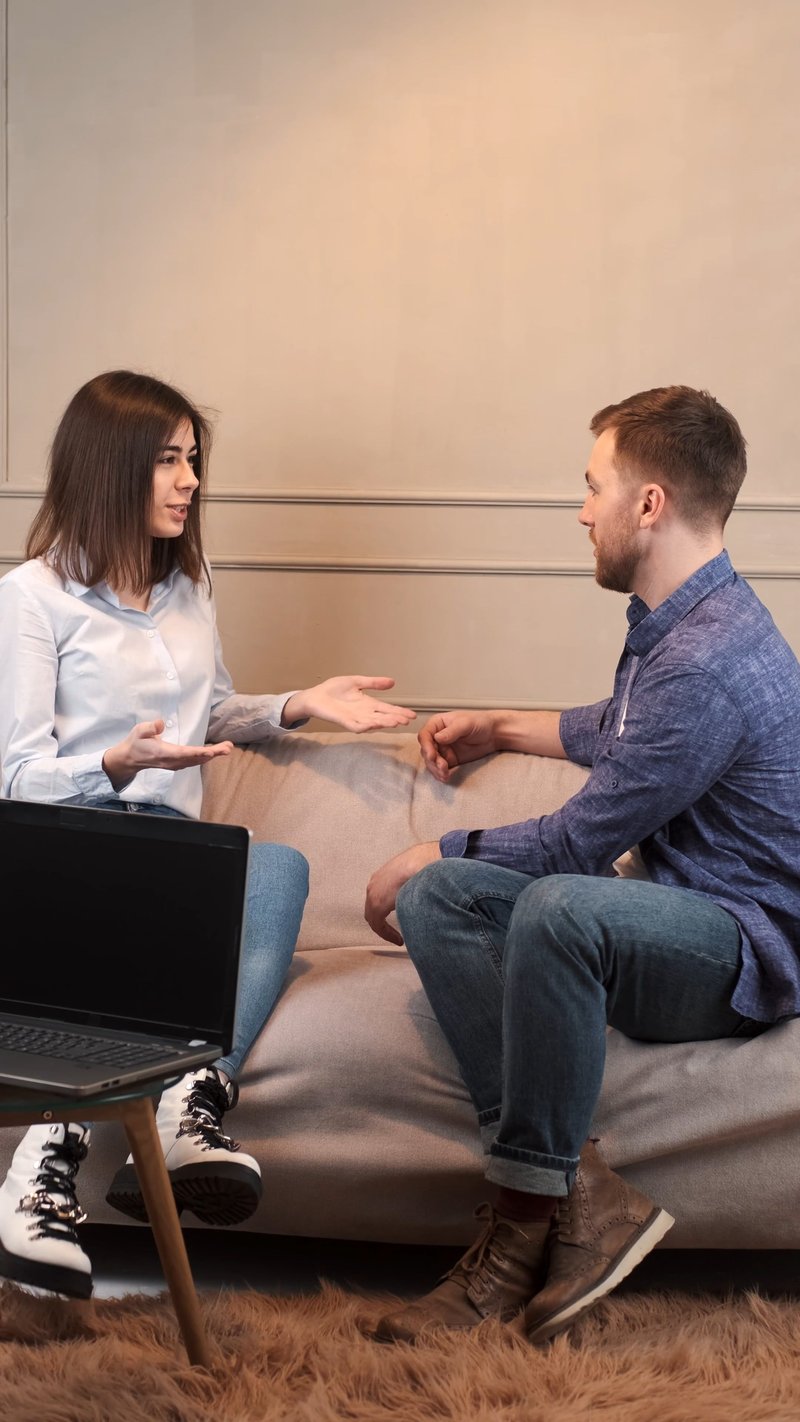 A Young Couple Arguing while Sitting on a Sofa A Young Couple Arguing while Sitting on a Sofa