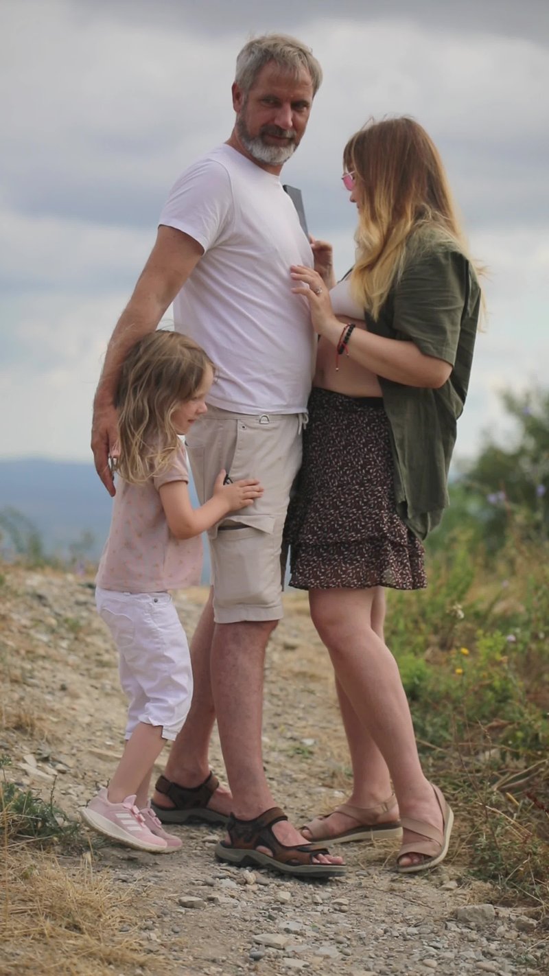 A family standing on a dirt road with a sign that says, the best way to  raise a child