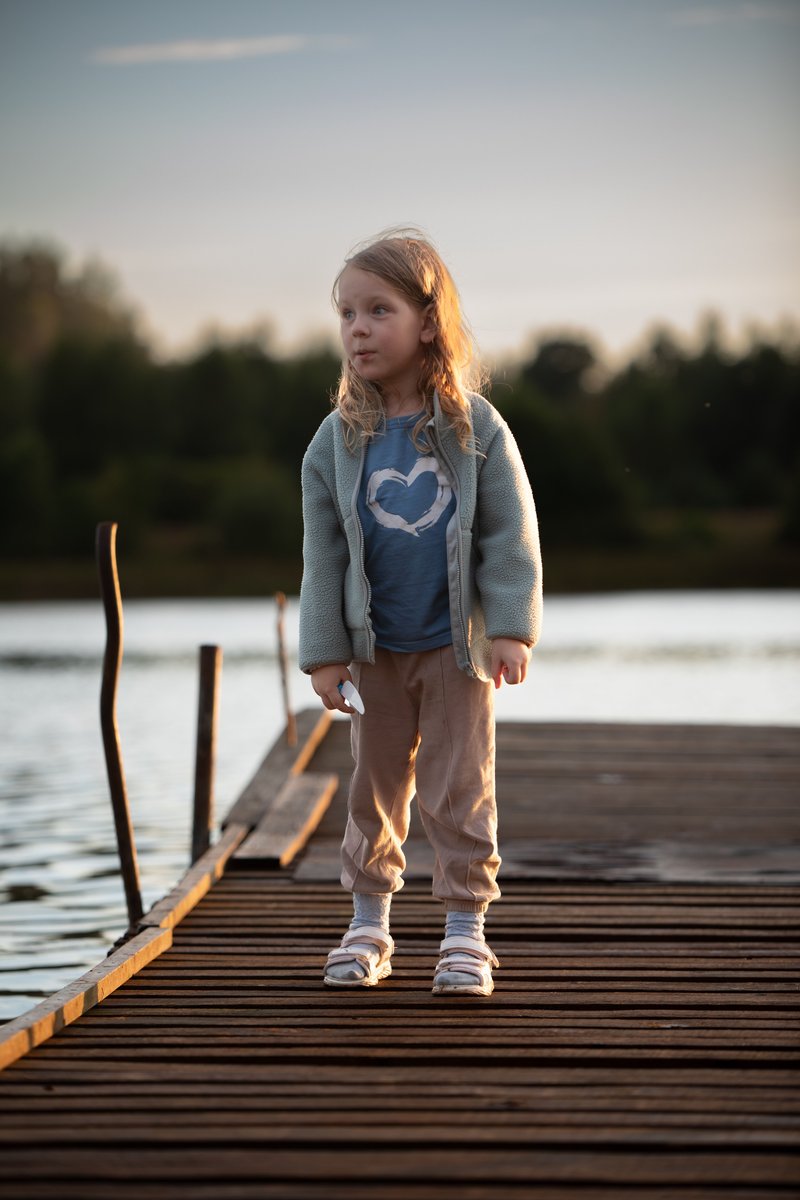A little girl crouching on a dock near a lake &middot; Free Stock Photo
