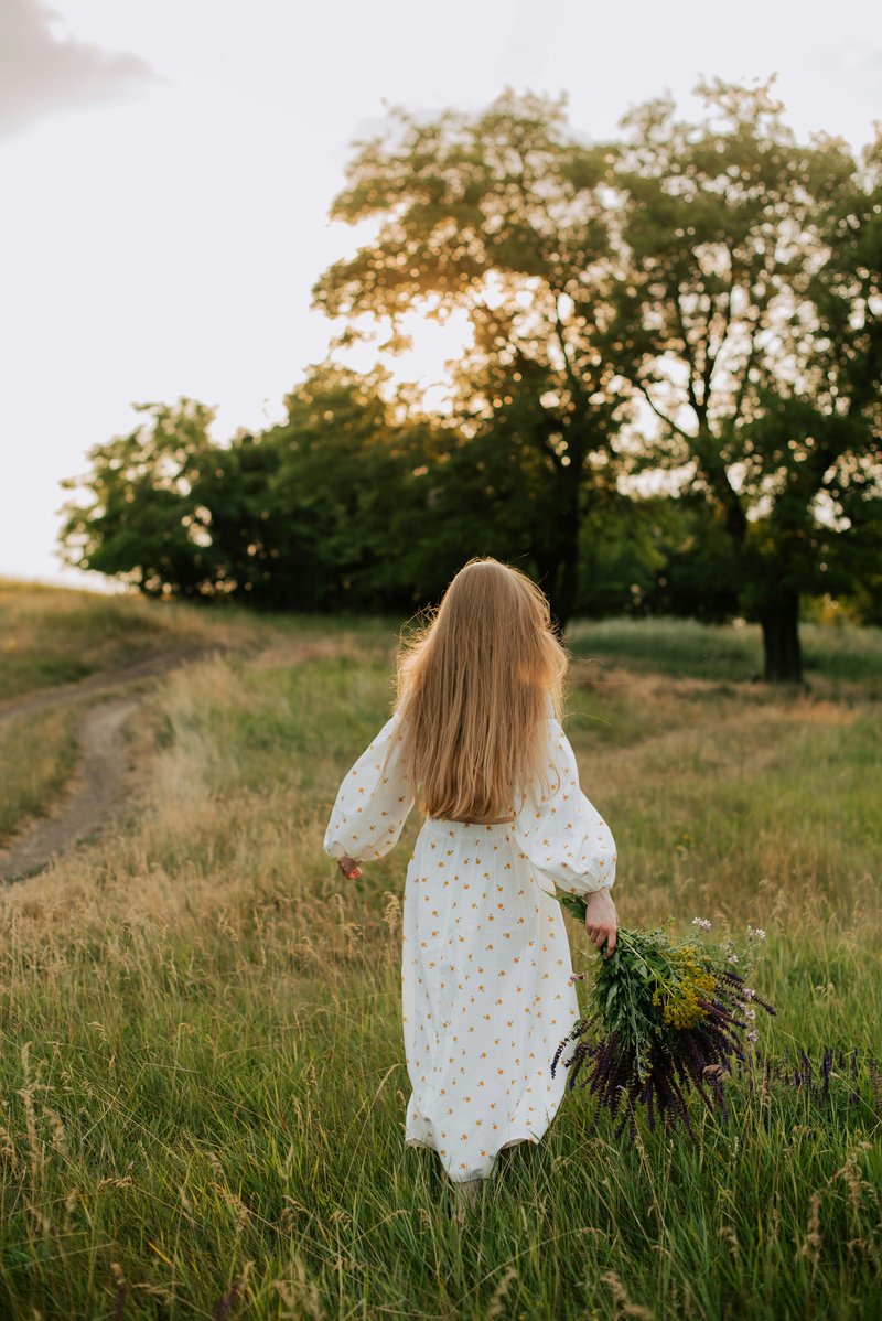 A little girl in a white dress walking through a field - Free Photo on  Unsplash