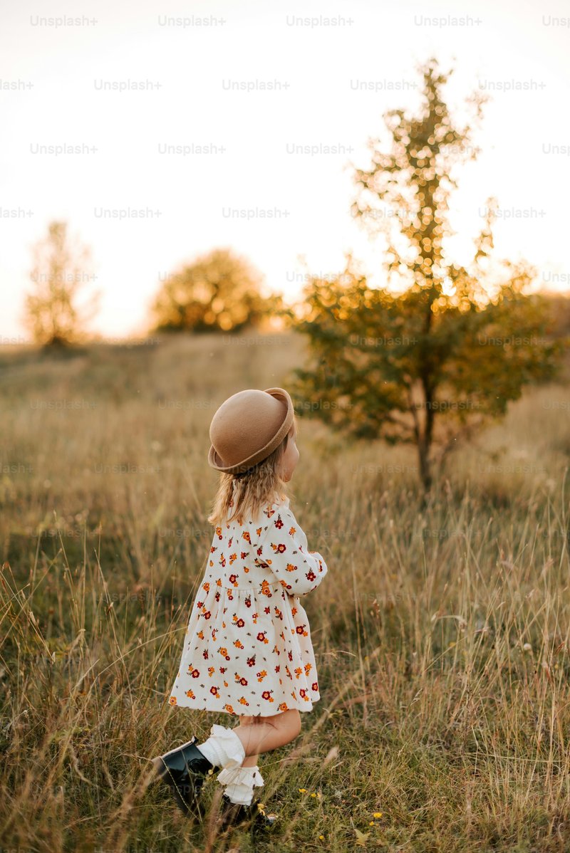 A little girl standing in a field with a hat on - Photo on ...