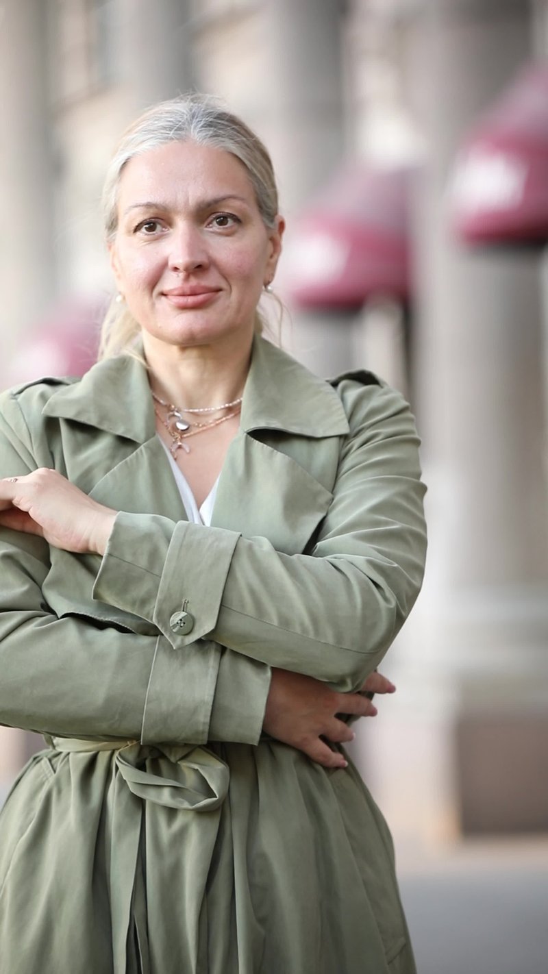 A woman in a trench coat standing in front of a building