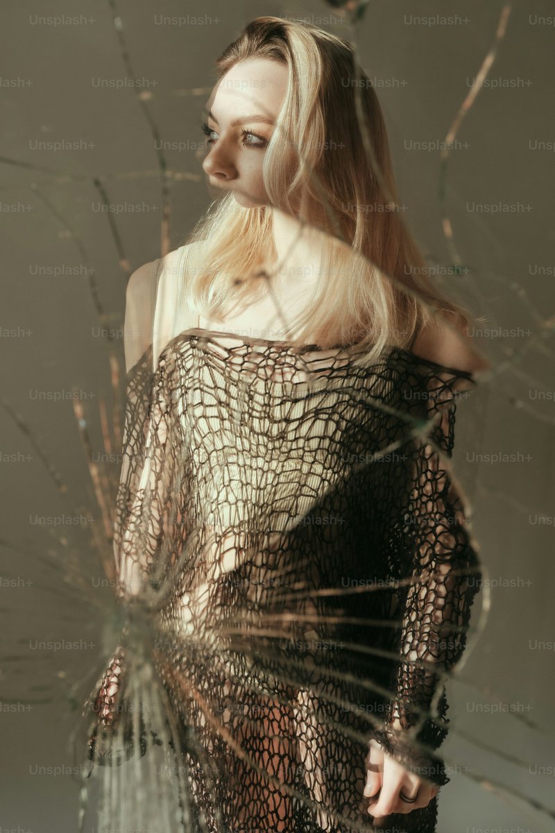A woman standing in front of a broken glass window photo – Green Image on Unsplash