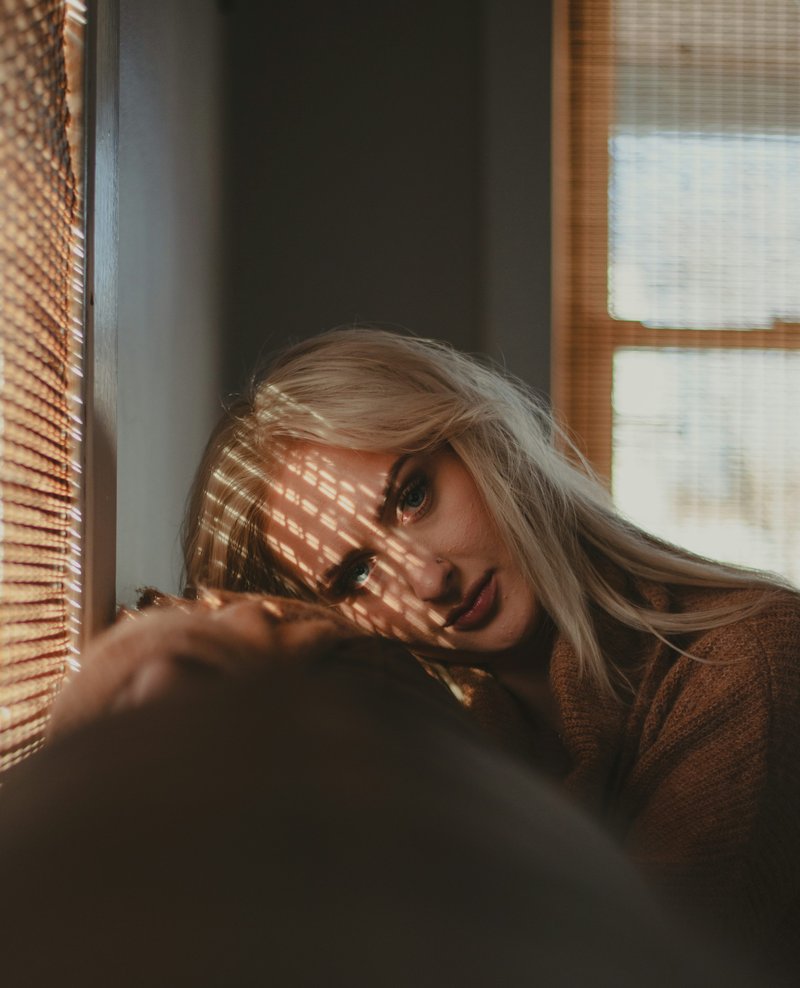 A woman with blonde hair is looking out a window - Free Photo on Unsplash