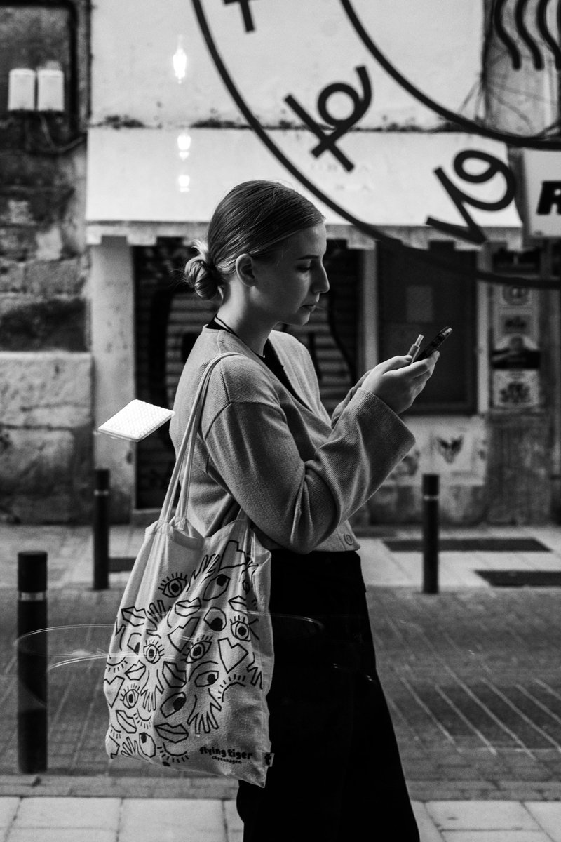 Black and White Shot of a Woman Checking her Smartphone in the Street · Free Stock Photo