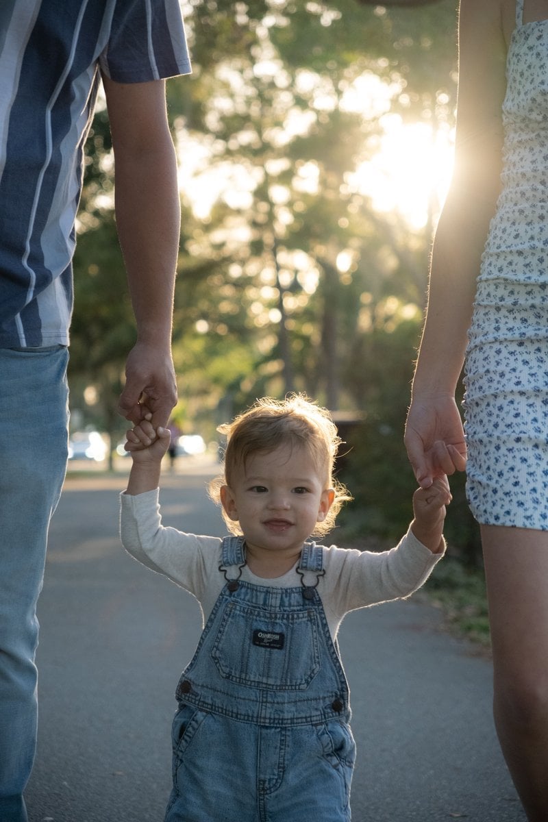 Boy Holding Hands with Mother and Father and Walking at Park · Free Stock Photo