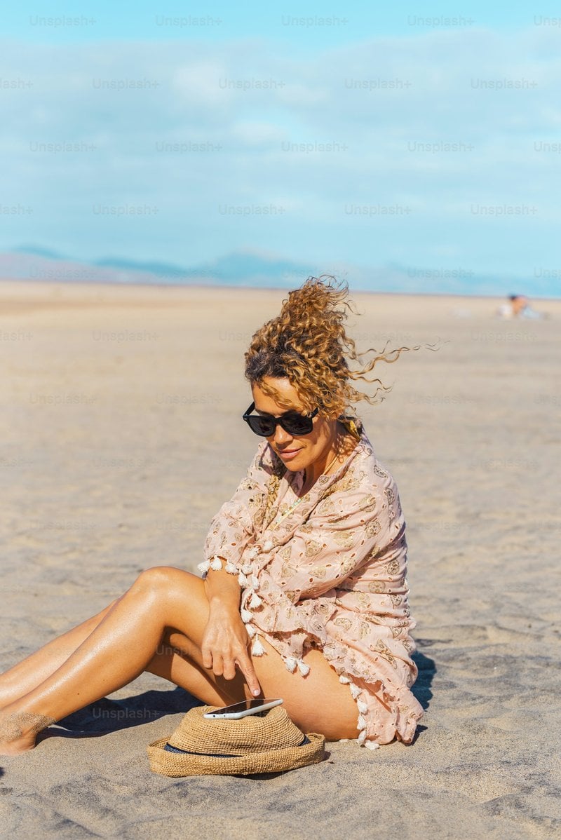 Female tourist relax under the sun in summer holiday vacation day at the beach using mobile phone. Attractive adult woman enjoy connection outdoors. Free solo single lady people in tourism activity photo –