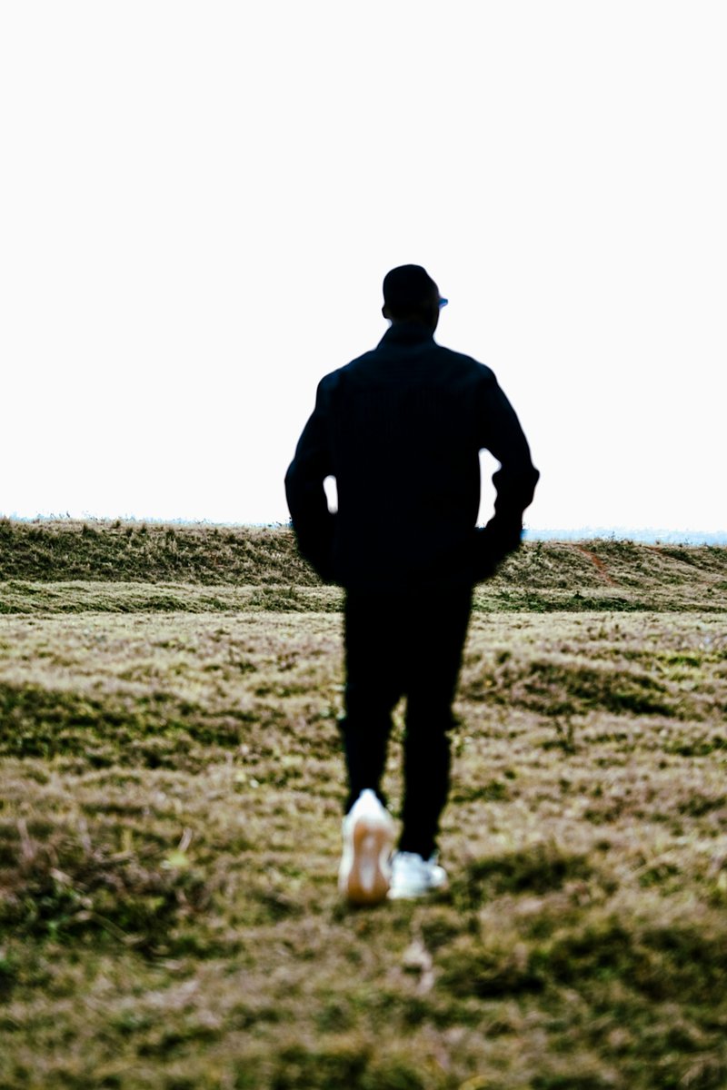 Man walking away in a grassy field photo – Free Green Image on Unsplash