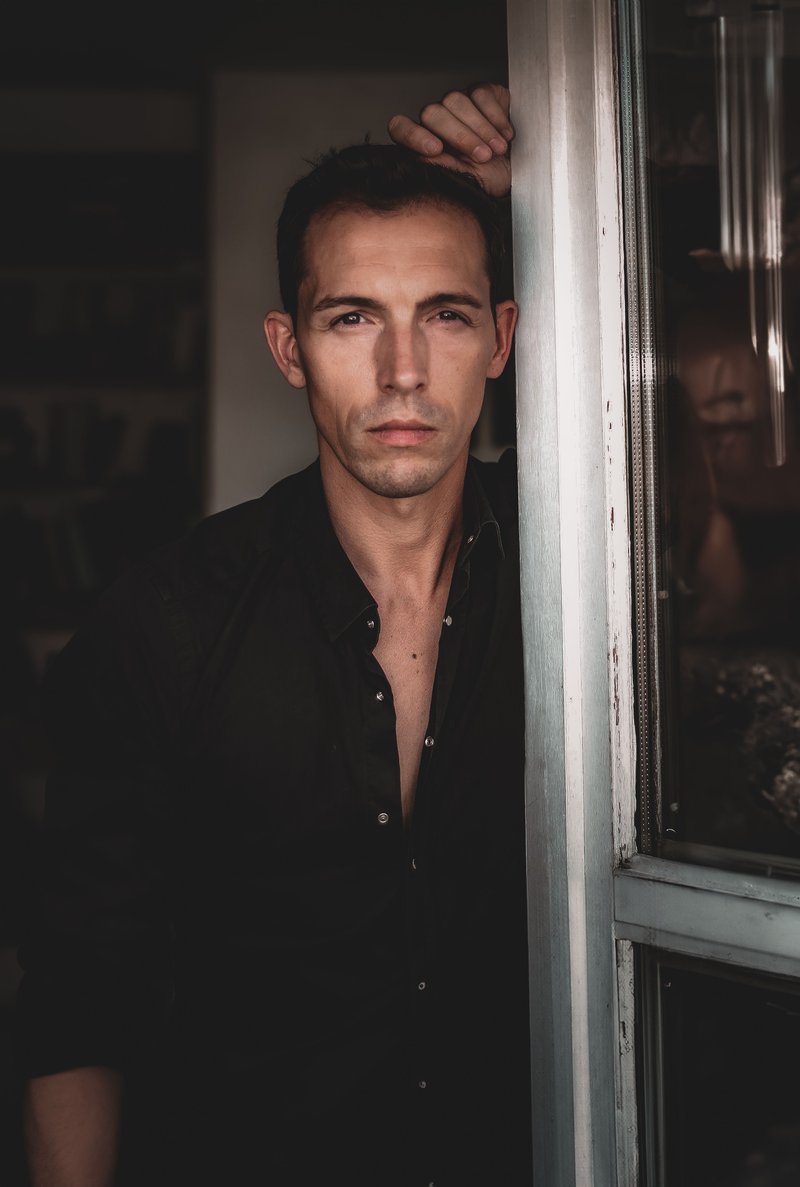 Man with a Serious Facial Expression Standing beside an Opened Window · Free Stock Photo