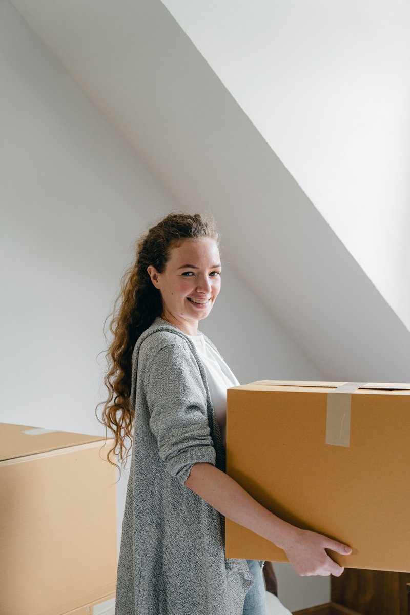 Smiling woman standing with big box in apartment · Free ... Smiling woman standing with big box in apartment · Free ...