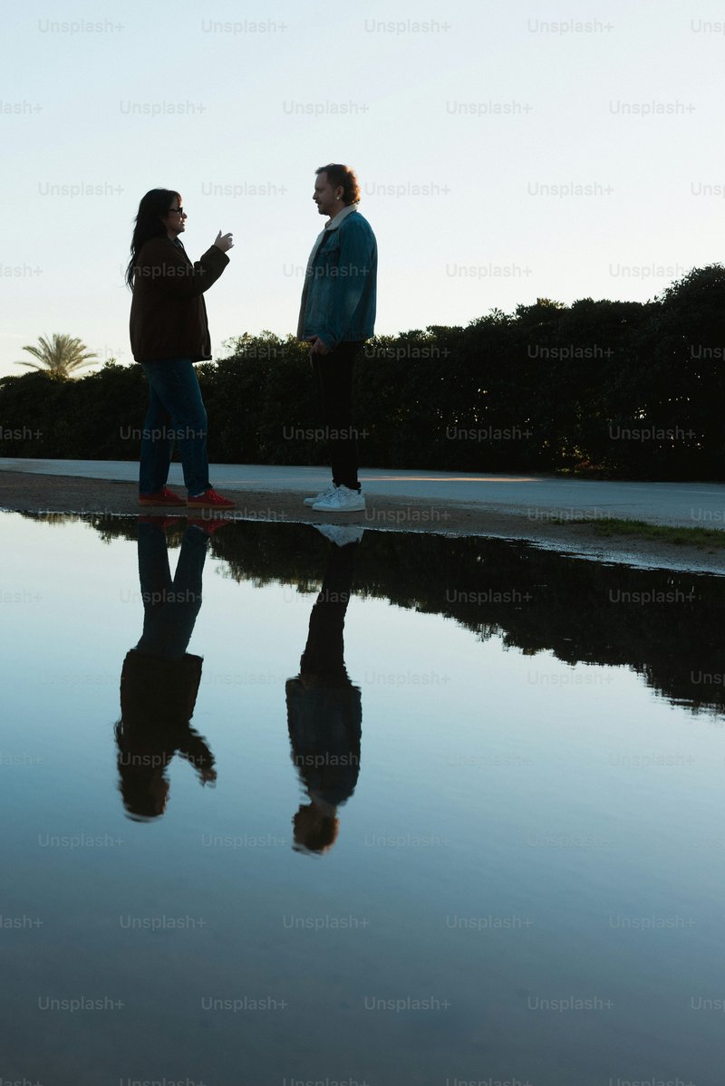 Two people talking by a reflective pool of water - Photo on ...