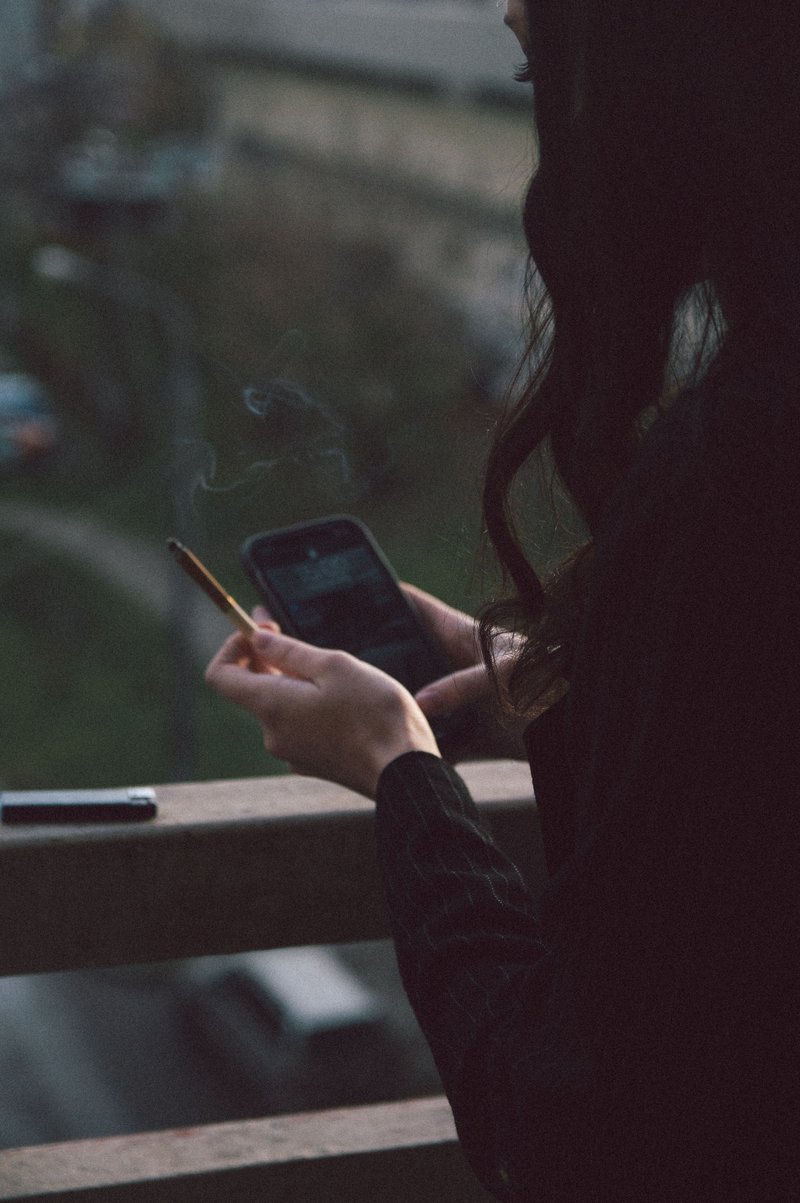 Woman Using Cellphone and Holding a Cigarette · Free Stock Photo