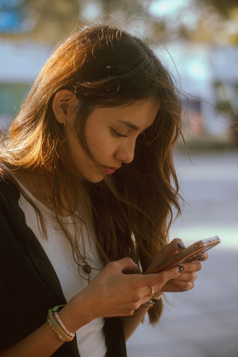 Woman using smartphone on city street · Free Stock Photo