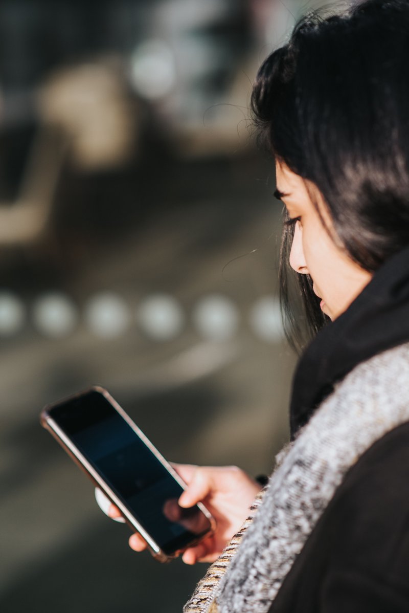 Woman using smartphone on city street · Free Stock Photo