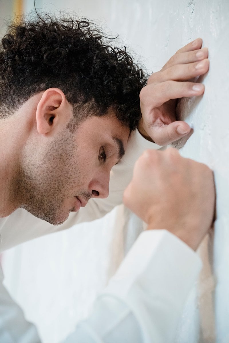 Man Leaning His Head on White Wall · Free Stock Photo