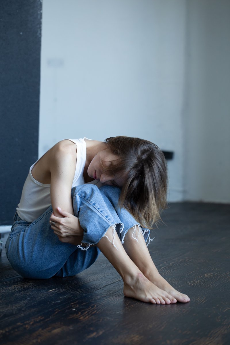 Woman in White Tank Top and Blue Denim Jeans Sitting on ...