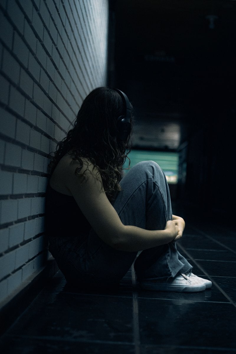 Young Woman Sitting Alone with Headphones in Hallway &middot; Free ...