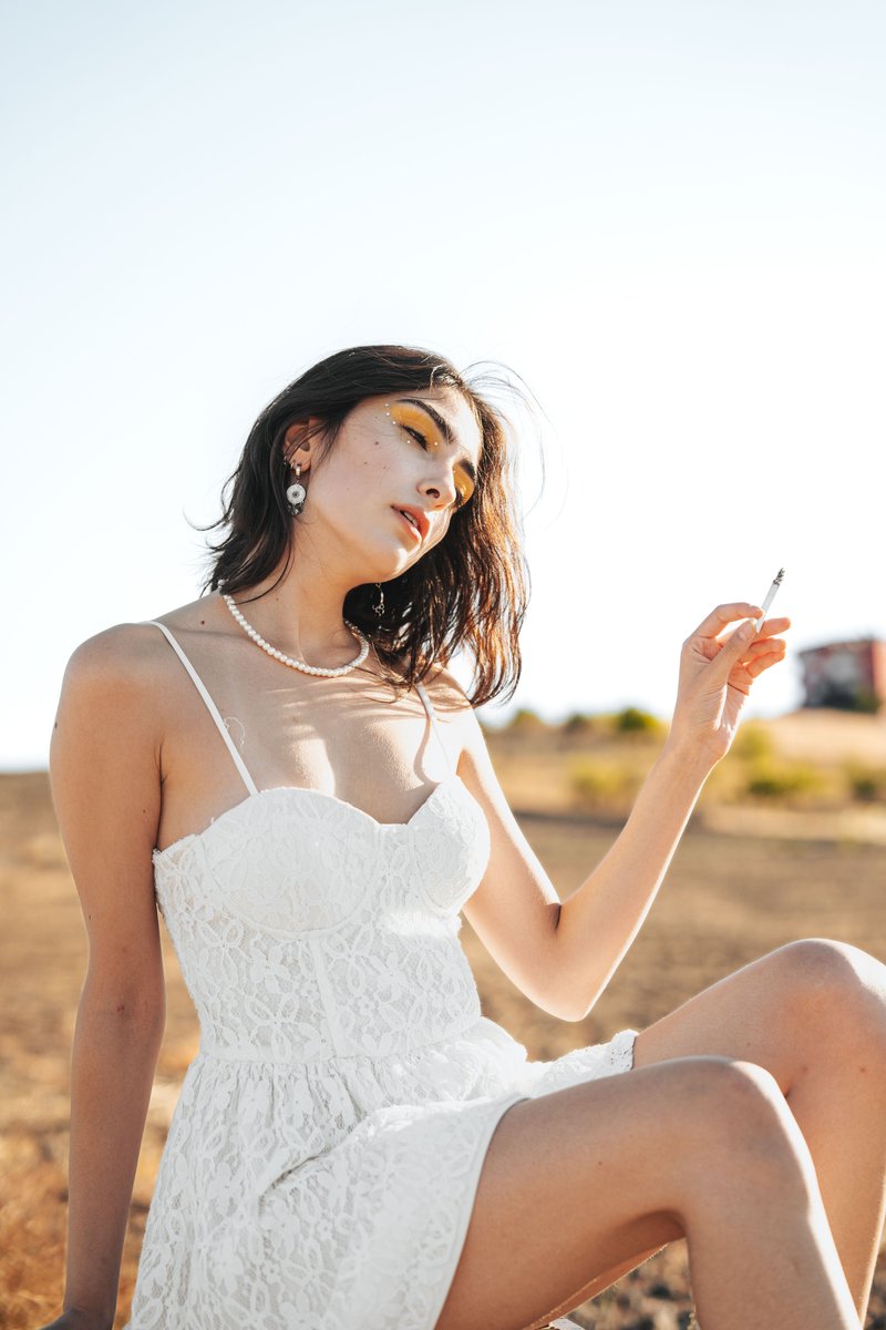Young Woman in a White Spaghetti Strap Mini Dress Sitting in ...